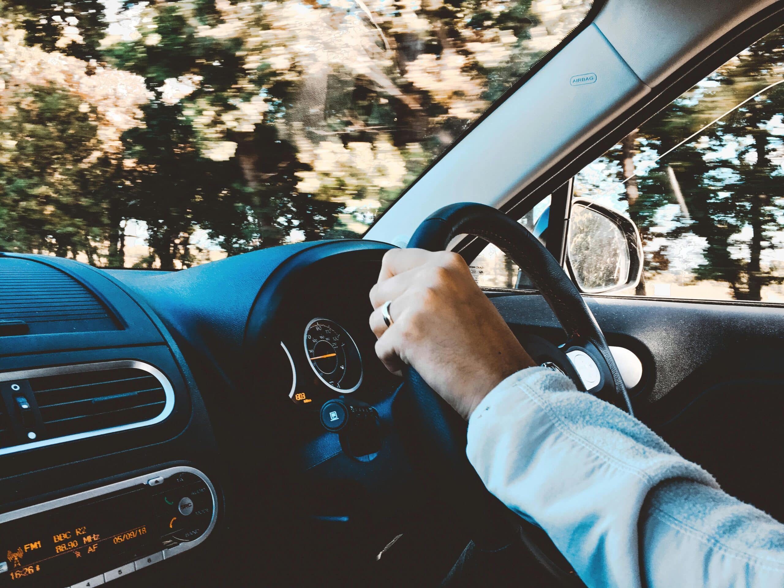 Hand on a wheel driving a car.
