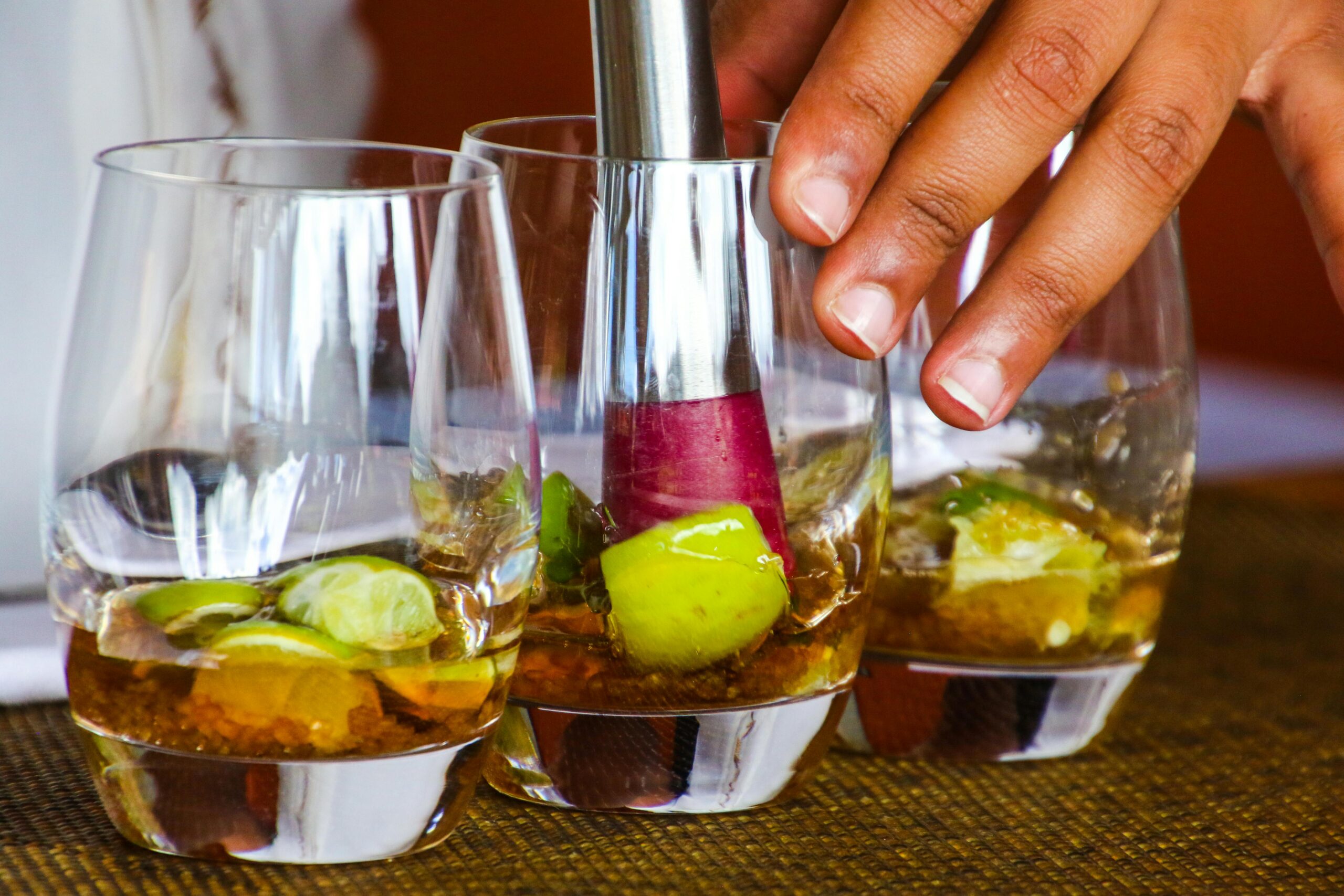 Three cocktail glasses being muddled.
