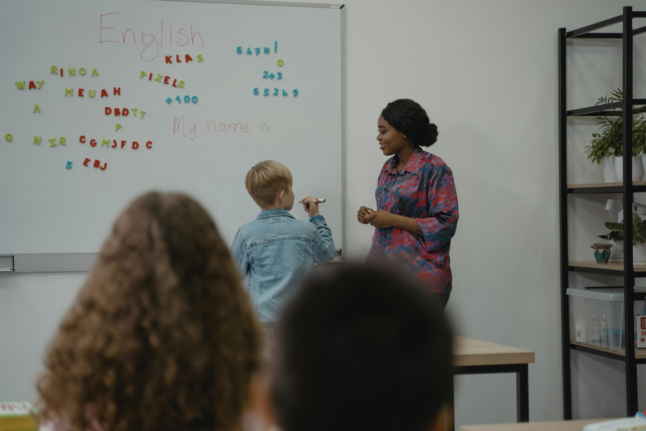Student at the white board with a teacher in a class.