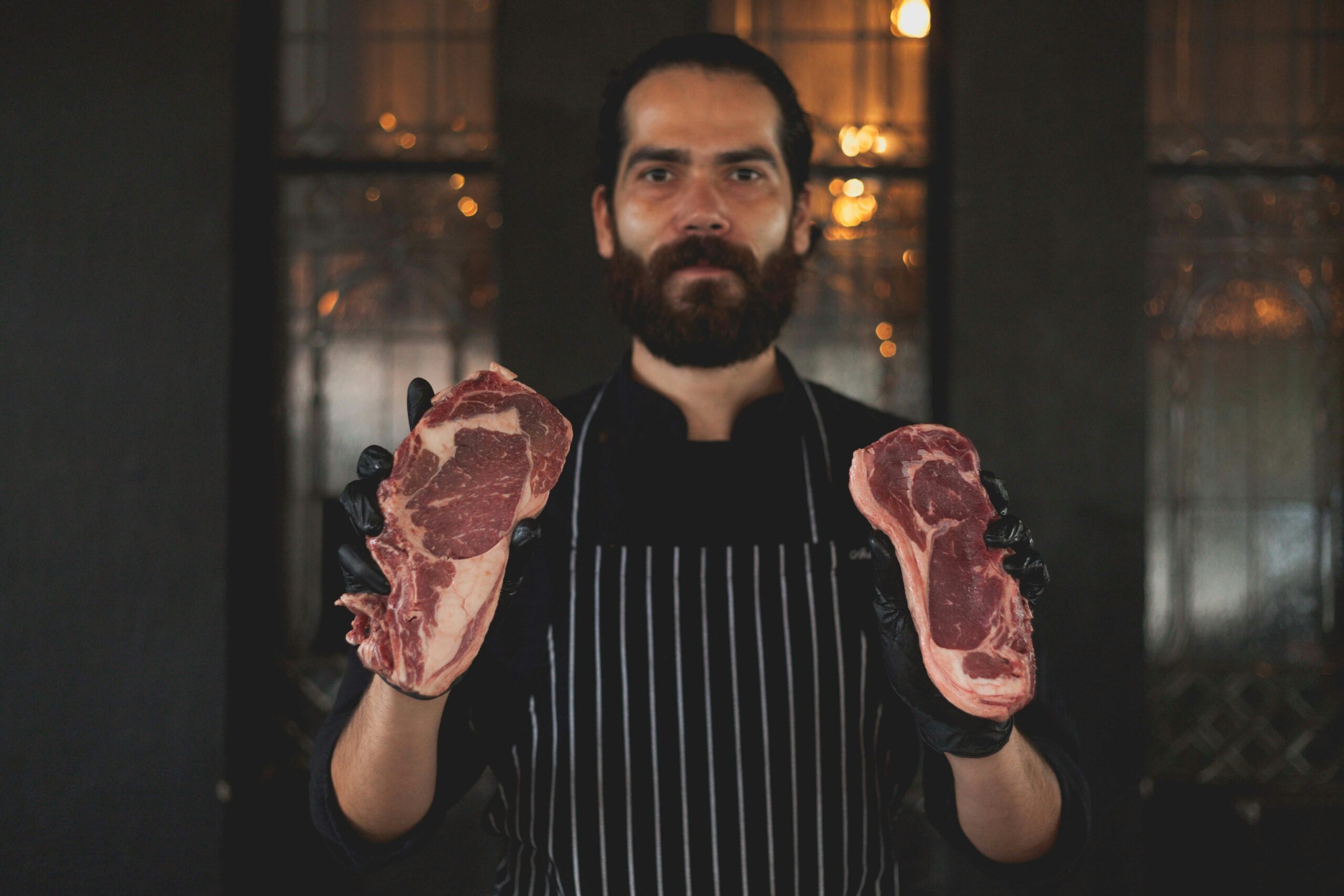 A butcher holding a steak in each of his hands.