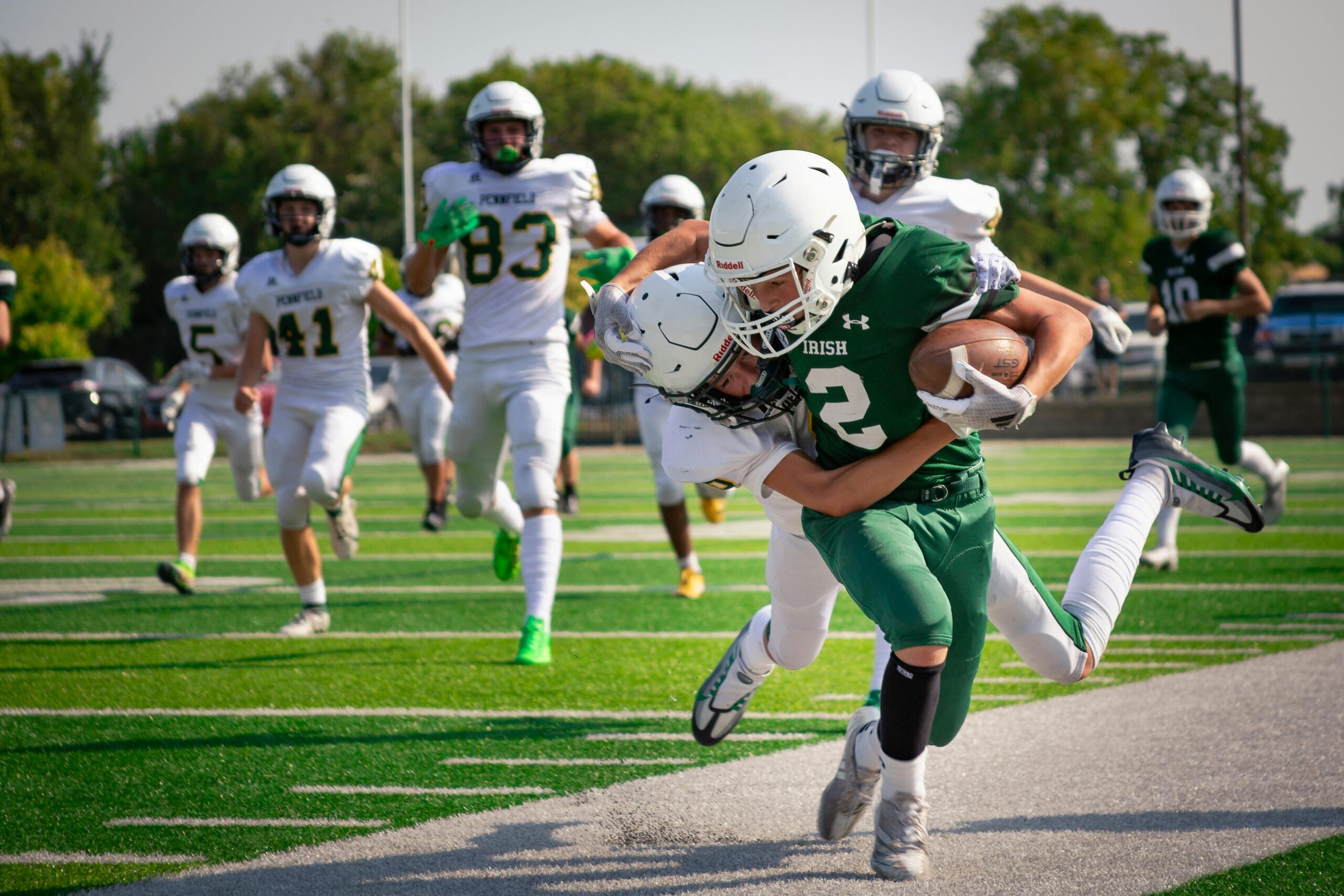 A football team wearing green and white jerseys playing on a field.
