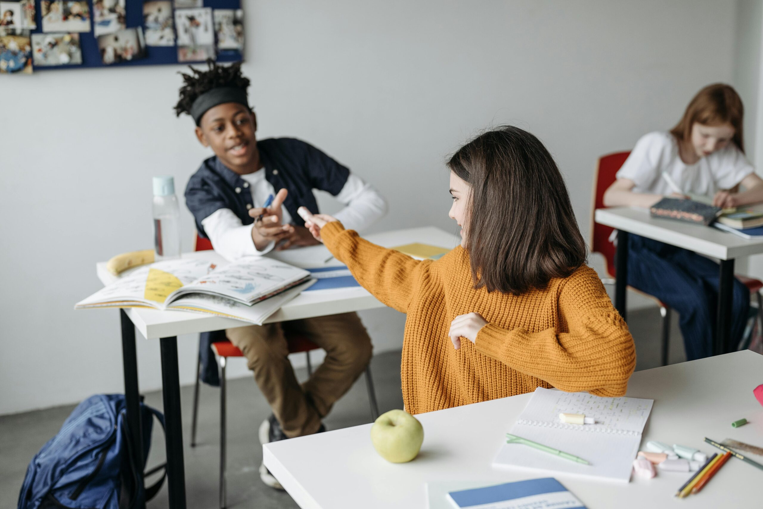 Students passing each other something in class.