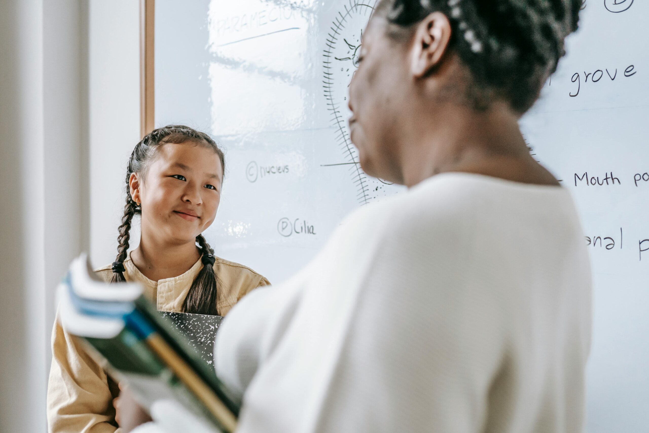 teacher holding books facing a student.