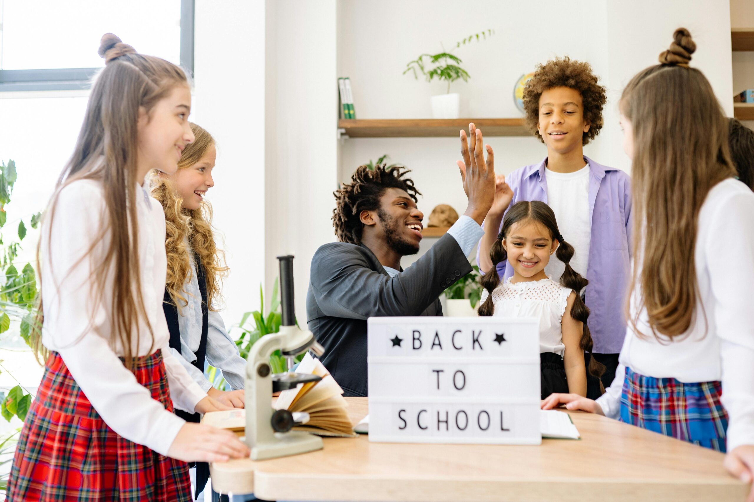 teacher and students with a back to school sign.