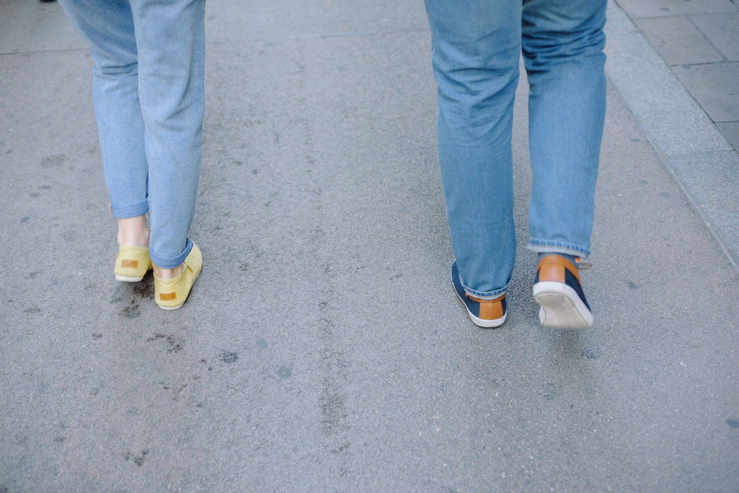 two sets of legs walking on concrete in running shoes.